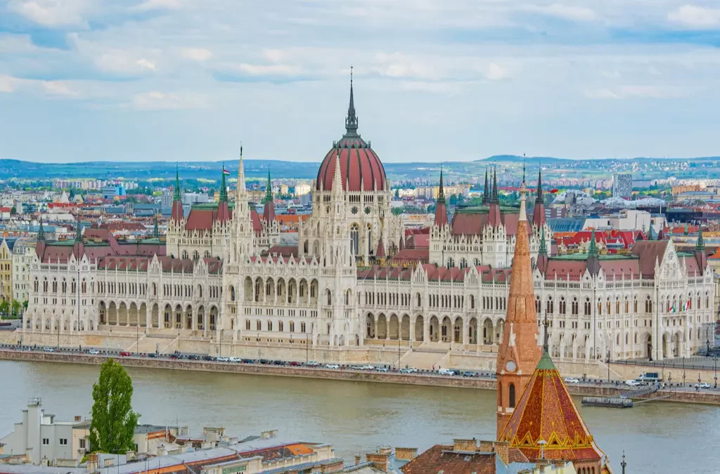 Vista do Parlamento Húngaro com sua cúpula majestosa e torres góticas.