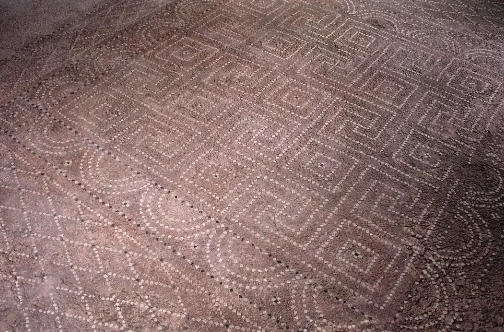"Mosaico romano detalhado no chão da Casa de la Fortuna.