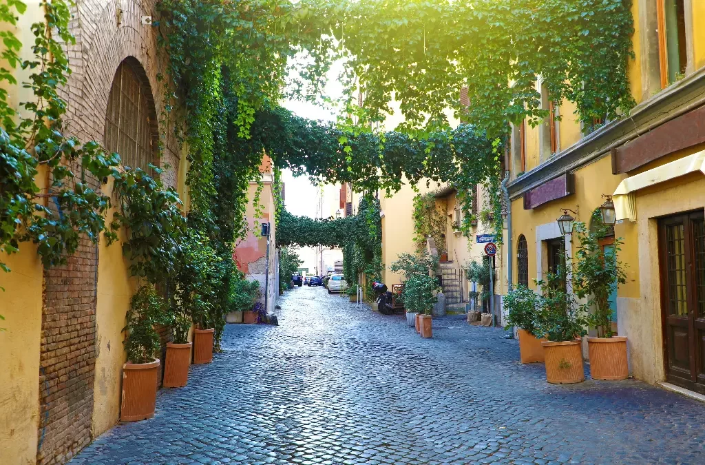 Rua de paralelepípedos em Trastevere com fachadas coloridas e atmosfera boêmia.